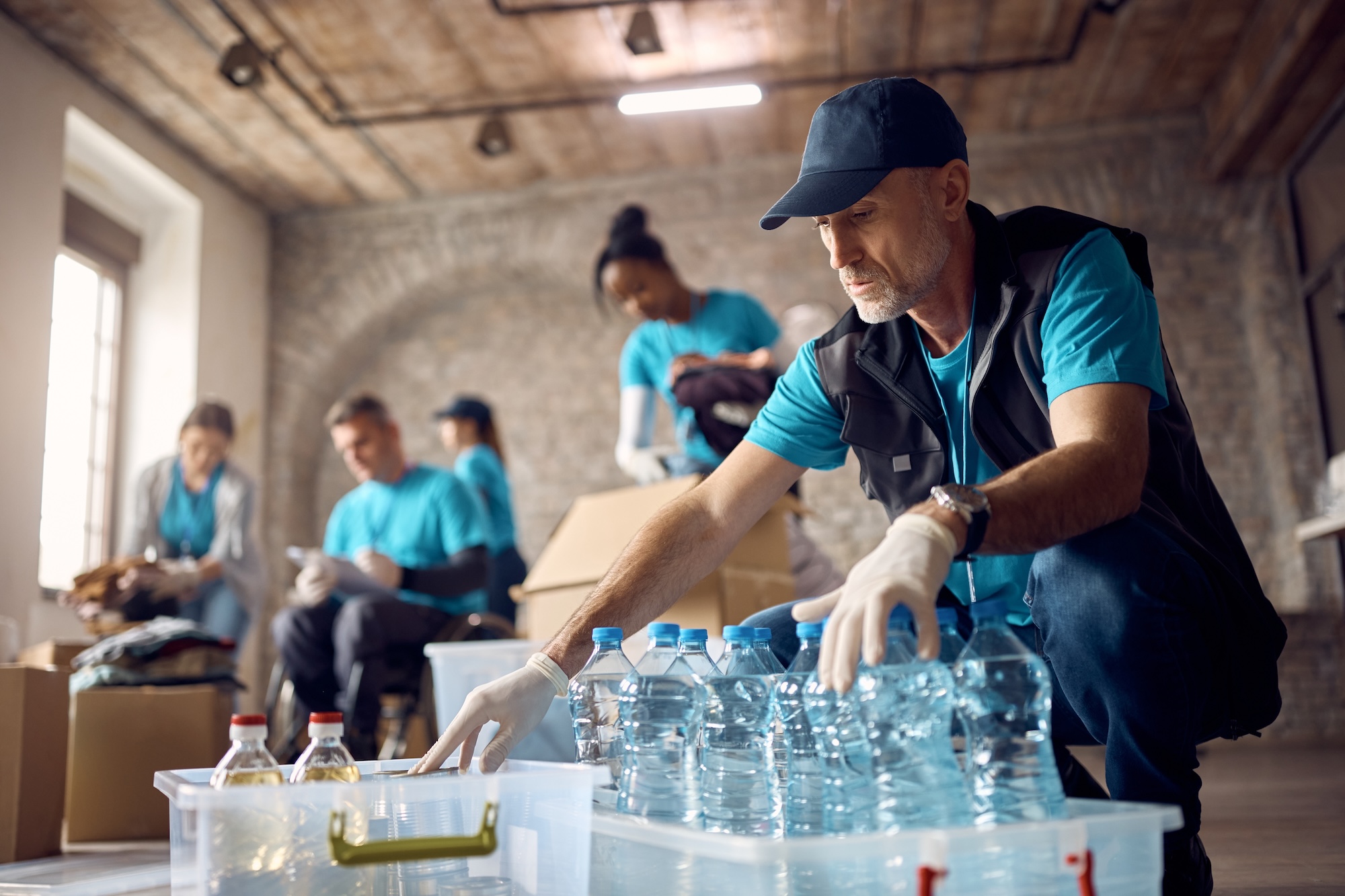 Professional nonprofit volunteers in turquoise uniforms coordinating disaster relief supplies showcasing community service and humanitarian aid